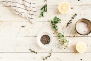 Fresh food ingredients, including a halved lemon, herbs, and dried lavender, arranged on a rustic wooden table for a natural and healthy food preparation scene.